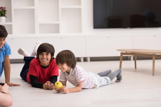 happy young boys having fun with an apple on the floor in a new modern home