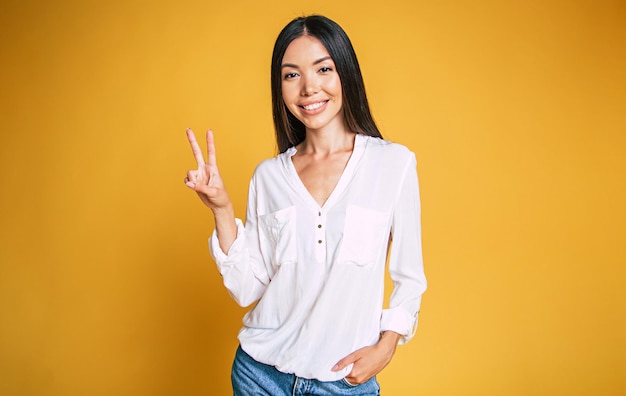 Happy young brunette asian woman portrait on yellow background