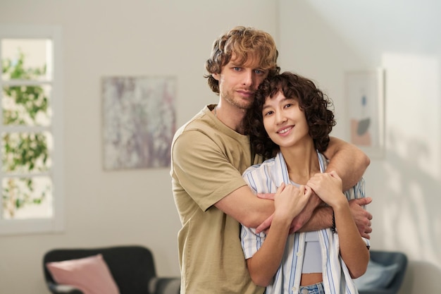 Happy young brunette woman enjoying embrace of her husband