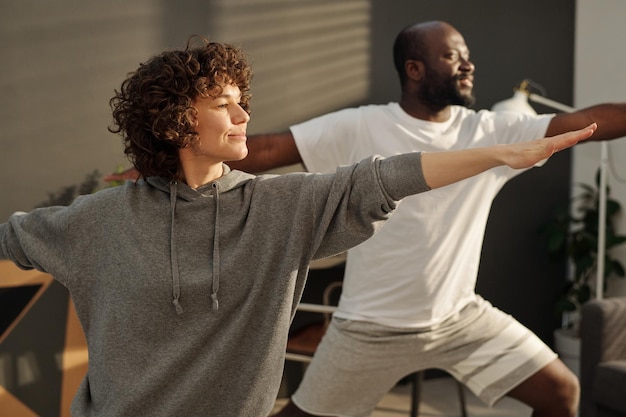 Photo happy young brunette woman in grey hoodie stretching arms during exercise