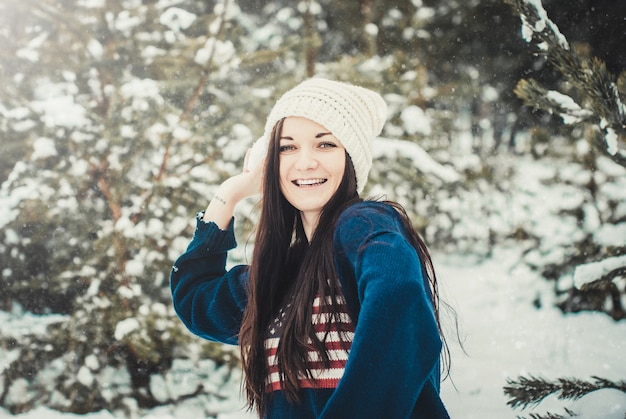 Happy young brunette woman throwing snow ball in winter park