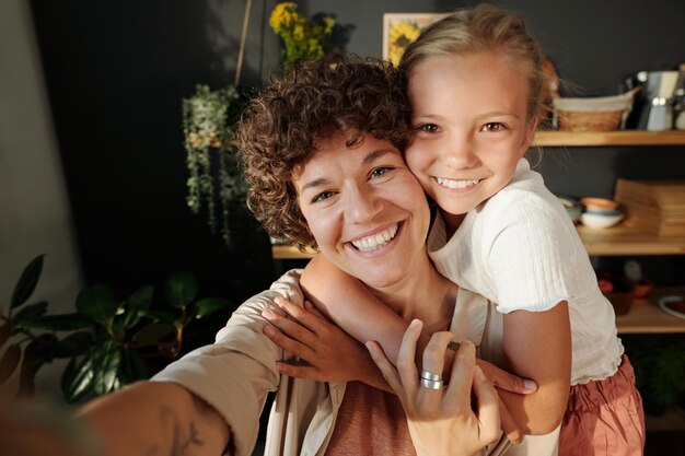 Happy young brunette woman with dark short curly hair and her youthful daughter