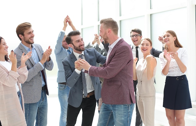 Happy young business man accepting congratulations from his colleagues