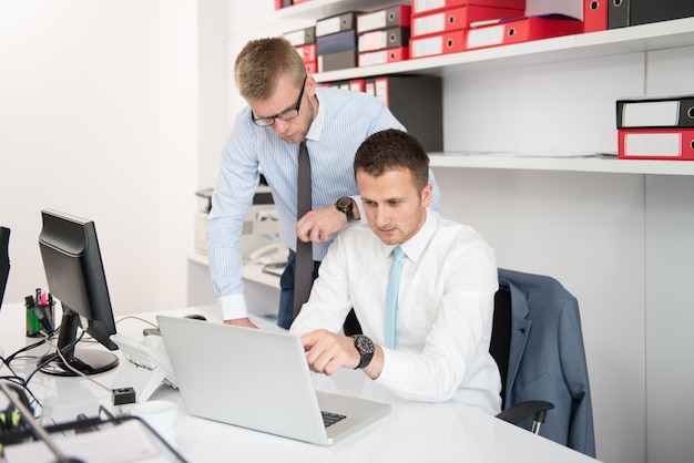 Счастливые молодые бизнесмены работают в современном офисе на компьютере