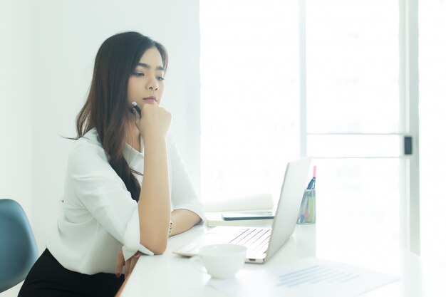 現代のオフィスで彼女のラップトップを見て、幸せな若いビジネスの女性。作業コンセプト。