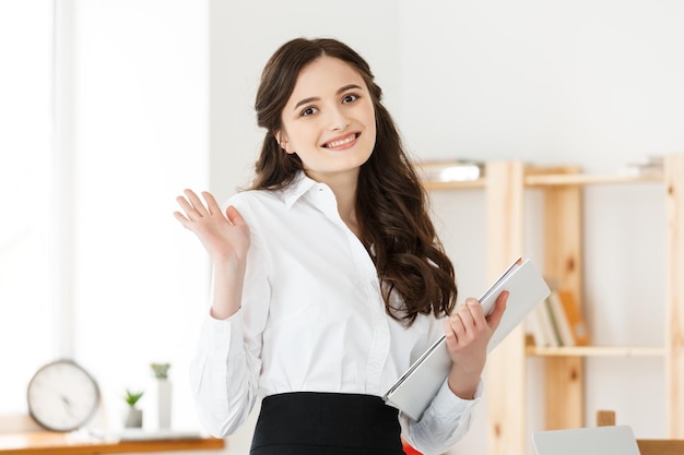 Happy young business woman or secretary holding document in modern office