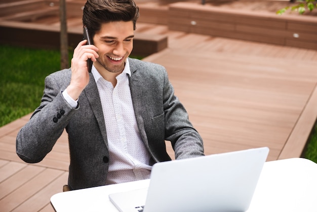 Happy young businessman dressed in suit talking