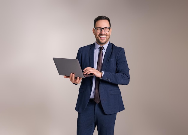Happy young businessman in eyeglasses doing online research over laptop against white background