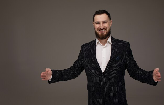 Happy Young Businessman Presenting Isolated Over Grey wall. Copyspace.