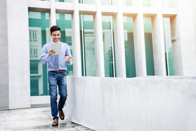 Happy Young Businessman use a digital tablet while walk