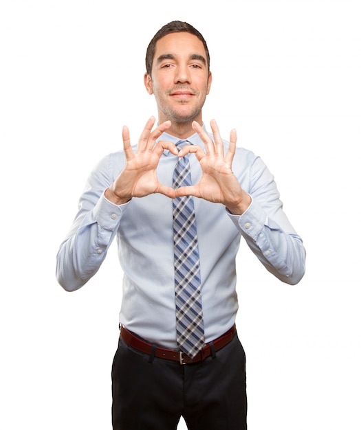 Happy young businessman with a love gesture