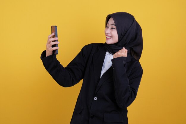 Happy young businesswoman getting good news on yellow