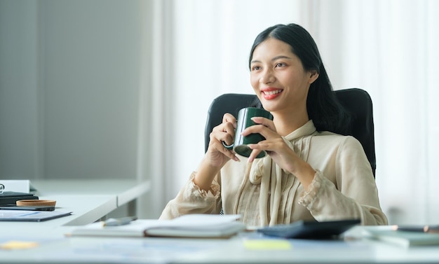 Happy young businesswoman sitting on comfortable office chair and enjoy her morning coffee