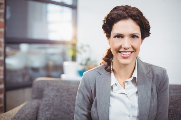 Happy young businesswoman sitting on sofa