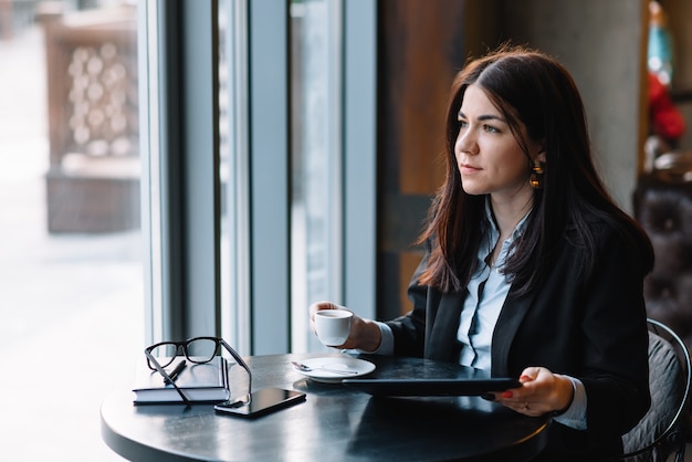 Happy young businesswoman using tablet computer in a cafe