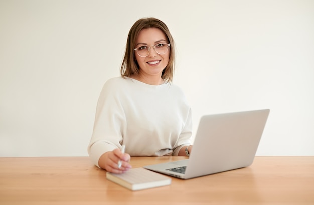 Happy young businesswoman working on netbook in office