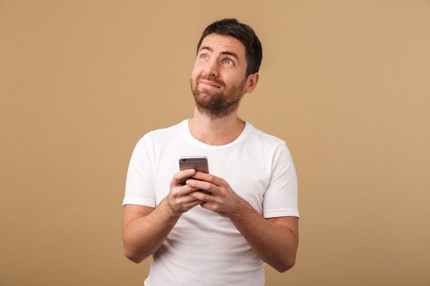 Happy young casual man holding mobile phone isolated