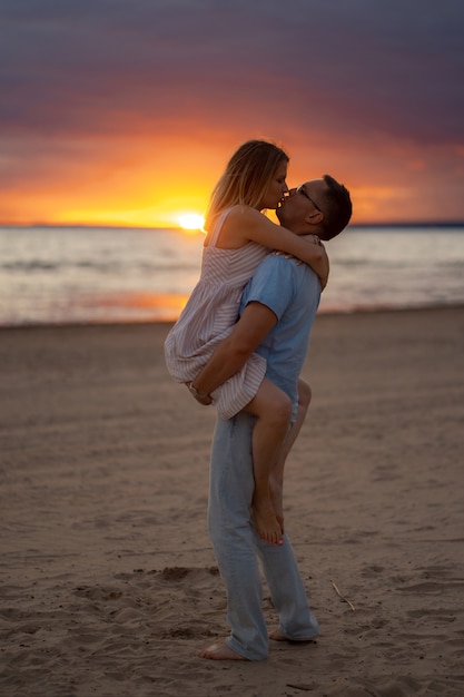 Happy young caucasian beautiful couple on sunset at the beach in summer Beautiful sky on background