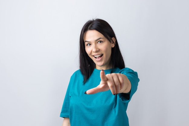Счастливая молодая кавказская женщина в синей футболке, указывая пальцами в сторону