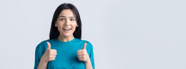 Happy young caucasian female in a blue tshirt making thumb up sign and smiling Good job