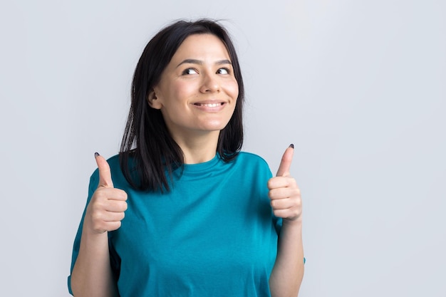 Happy young caucasian female in a blue tshirt making thumb up sign and smiling Good job