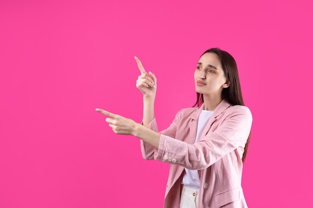 Happy young caucasian female in a pink jacket pointing fingers away