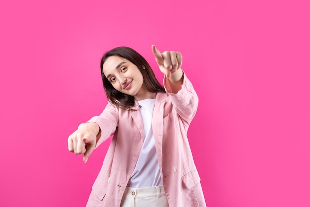 Foto una giovane donna caucasica felice con una giacca rosa che indica le dita