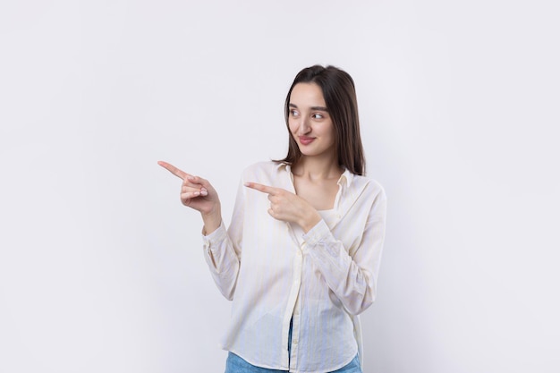 Happy young caucasian female in a shirt pointing fingers away