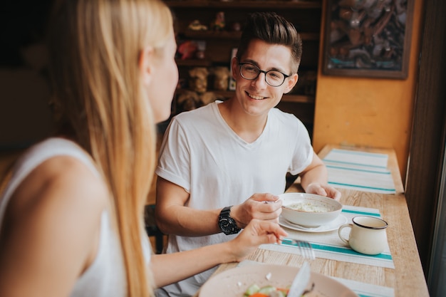 Happy young ccouple in love having a nice date in a bar or restaurant. they telling some stories about themself , drinking tea or coffee and and eating salad and soup.