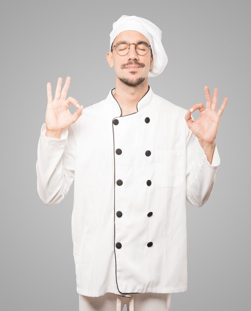 Happy young chef doing a gesture of meditation