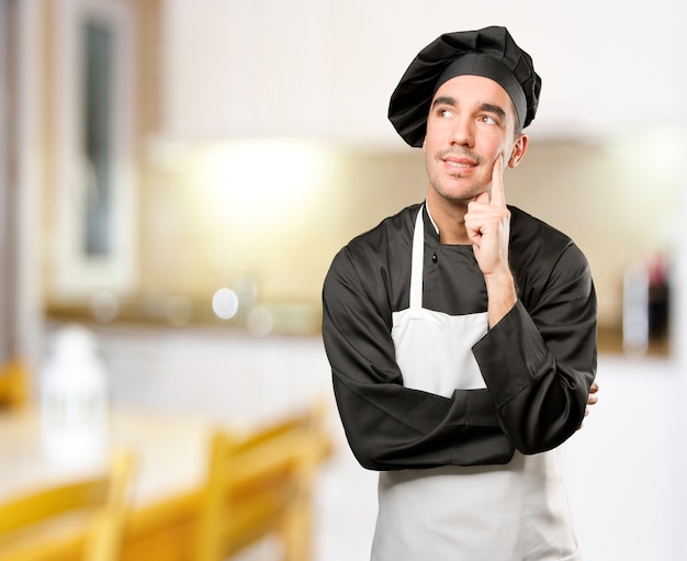 Счастливый молодой шеф-повар сомневается