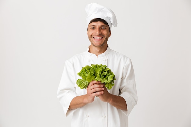 Happy young chef isolated on white holding salad.