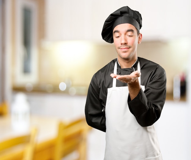 Happy young chef with a hold gesture