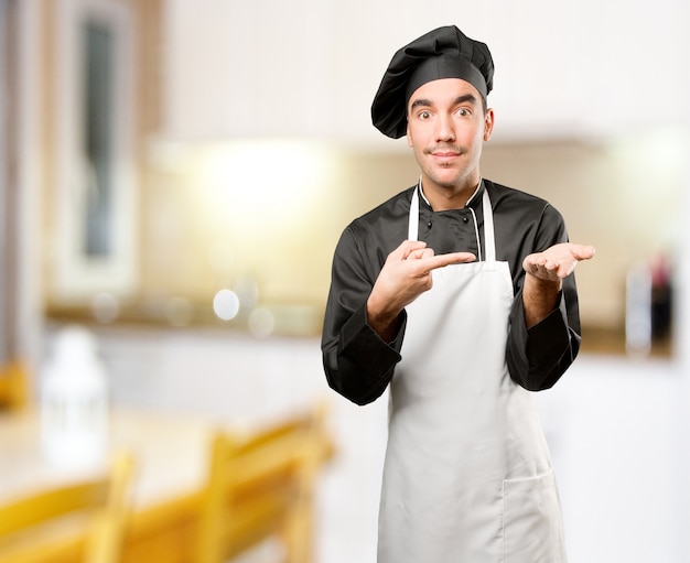 Foto felice giovane chef con un gesto di tenere