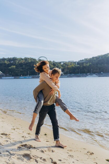 Happy young couple on the beach The guy holds the girl in his arms standing on the sandportrait of a couple in love