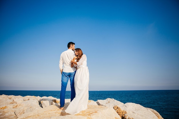 Happy young couple on the beach in love embracing and hugging smiling