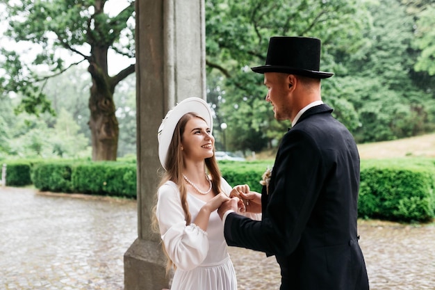 Happy young couple brides in hats young girl in a white wedding\
dress and hat with a bouquet of flowers brides in the castle bride\
and groom