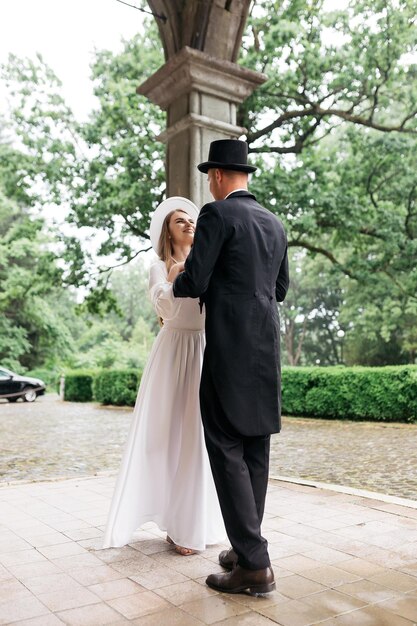 Happy young couple brides in hats young girl in a white wedding
dress and hat with a bouquet of flowers brides in the castle bride
and groom