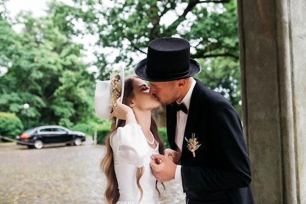 Happy young couple brides in hats young girl in a white wedding\
dress and hat with a bouquet of flowers brides in the castle bride\
and groom