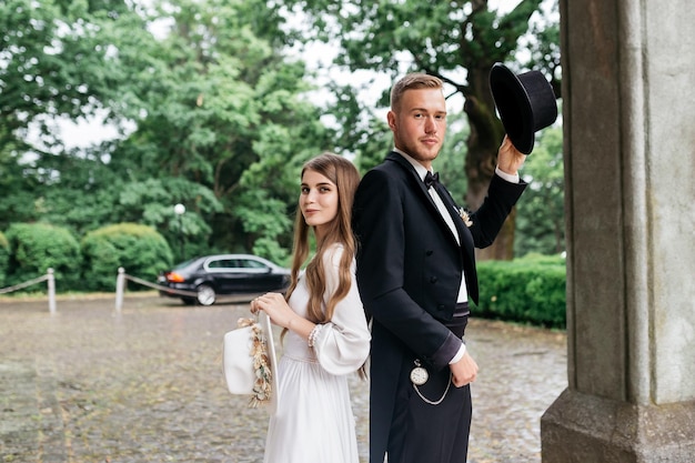 Счастливая молодая пара Невесты в шляпах Молодая девушка в белом свадебном платье и шляпе с букетом цветов Невесты в замке Жених и невеста