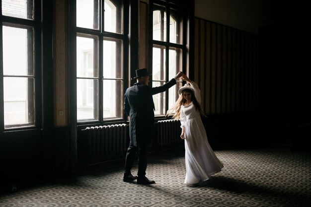 Happy young couple brides in hats young girl in a white wedding
dress and hat with a bouquet of flowers brides in the castle bride
and groom