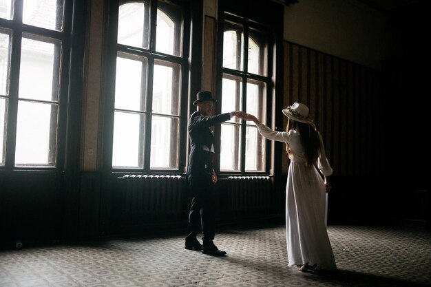 Happy young couple brides in hats young girl in a white wedding\
dress and hat with a bouquet of flowers brides in the castle bride\
and groom