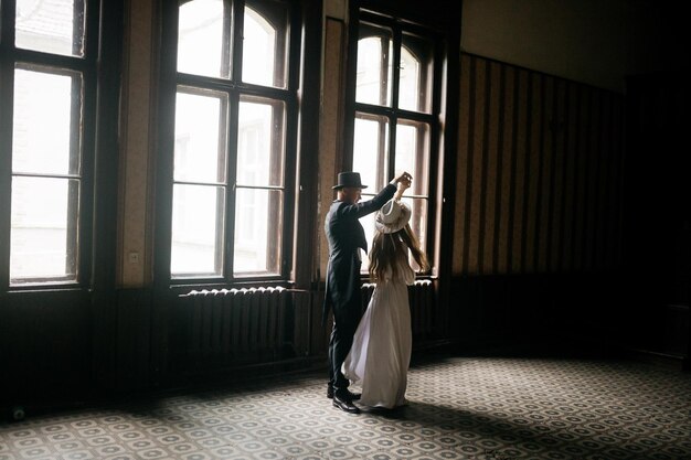 Happy young couple brides in hats young girl in a white wedding\
dress and hat with a bouquet of flowers brides in the castle bride\
and groom