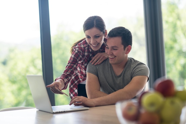 happy young couple buying online using laptop a computer and a credit card in their luxury home villa