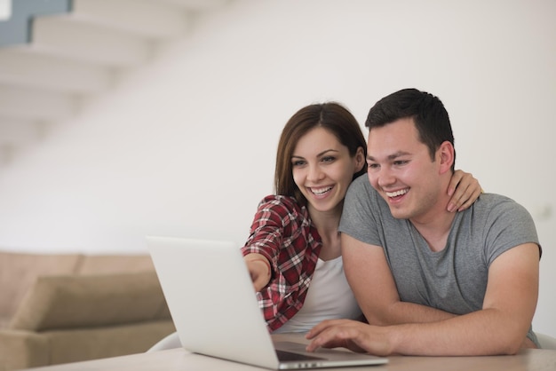 happy young couple buying online using laptop a computer and a credit card in their luxury home villa