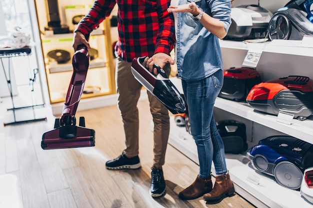 Happy young couple buying vacuum cleaner in store.