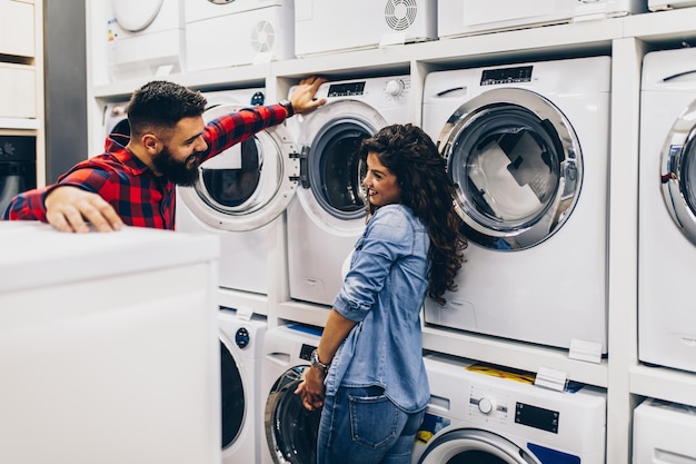 Happy young couple buying washing machine in appliances\
store.