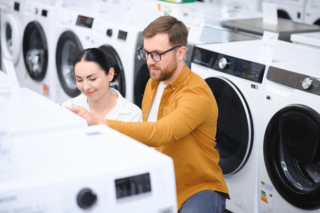 happy young couple buying washing machine in store