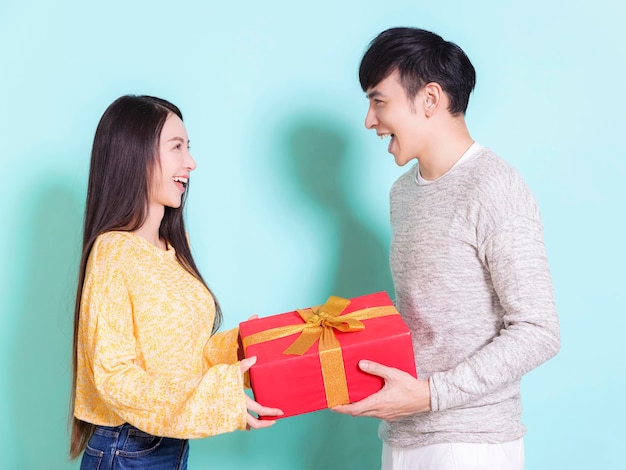 Happy young couple celebrating for chinese new year and holding gift boxIsolated on blue background