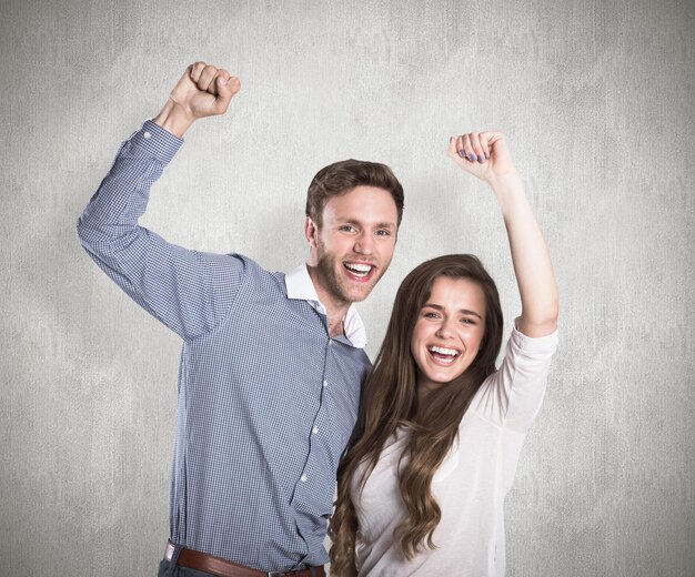 Happy young couple cheering against weathered surface